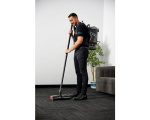Man using "Cleanstar T1" backpack vacuum on patterned carpet in office setting.